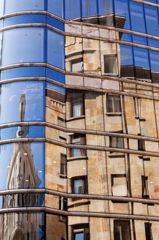 reflection of stone facade on modern glass facade