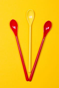Set of multi-colored long spoons on a yellow background
