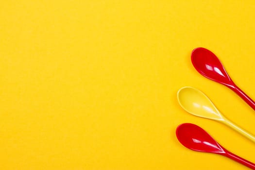 Set of multi-colored long spoons on a yellow background