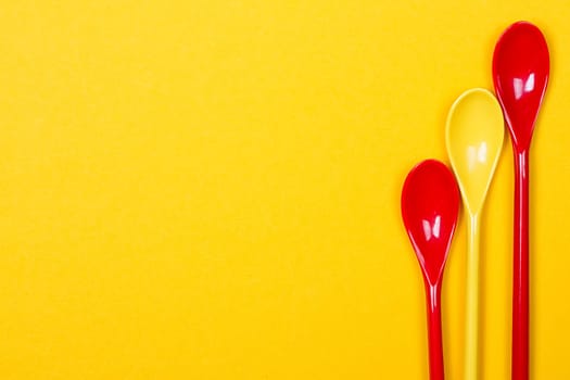 Set of multi-colored long spoons on a yellow background