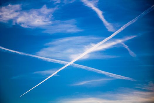 White chemtrails on blue sunny sky in spring.