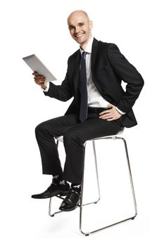 Cheerful young businessman sitting on a chair and smiling to the camera. Isolated on white background.