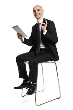 Happy young businessman sitting on a chair and smiling to the camera