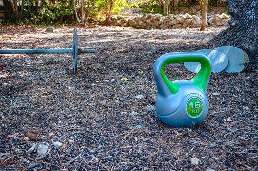 Homemade gym in a garden with barbell and ketttlebell