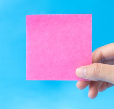 woman hand holding pink paper on blue background