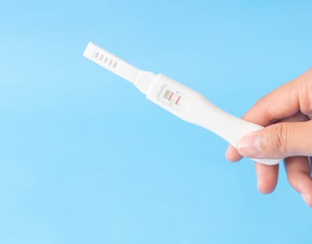 Hand holding pregnancy test with blue background, health care and medical concept