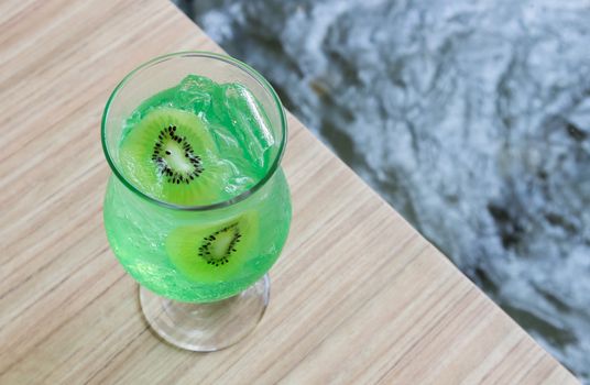 Closeup glass of kiwi soda on wood table, selective focus