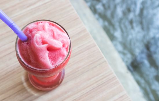 Closeup top view of watermelon smoothie in glass on wood table, selective focus