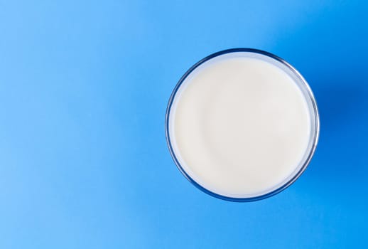 Closeup top view milk glass on blue background, healthy food concept
