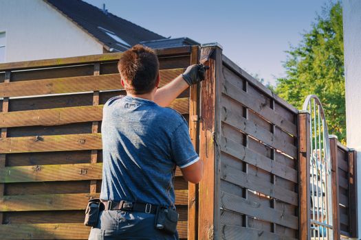 Man with artificial heart strokes a wood fence in the garden.