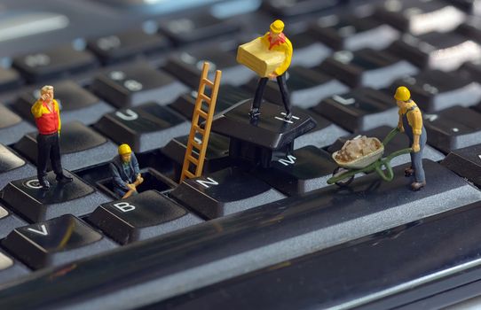 Workers figurines repairing keyboard