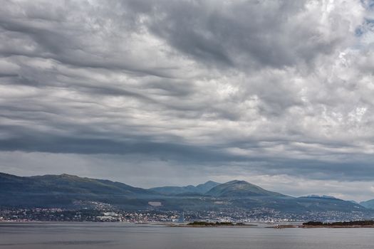 City and mountains along the Romsdalsfjorden near Andalsnes under a cloudy sky, Norway