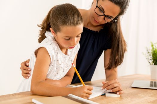 Young mother helping her daughter with homework at home