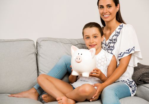 Mother and daughter with a piggy bank for her future savings