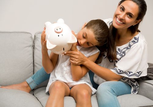 Mother and daughter with a piggy bank for her future savings