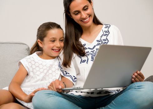 Mom teaching Daughter working with a a laptop at home