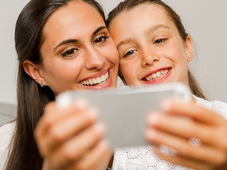 Beautiful Mom and Daughter at home, showing something on the phone