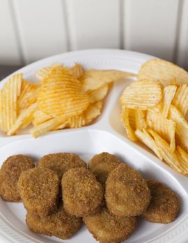 A stack of chicken nuggets and two heaps of potato chips