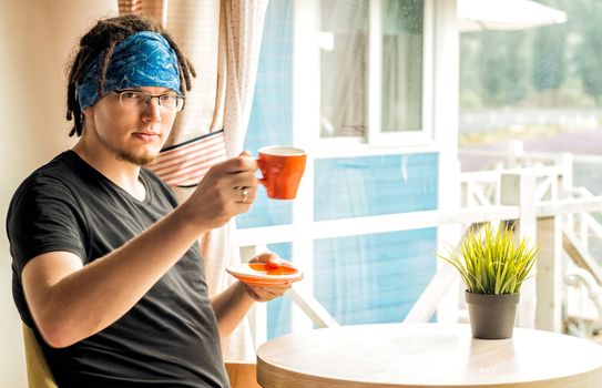 a young man with dreadlocks is drinking tea at the hotel