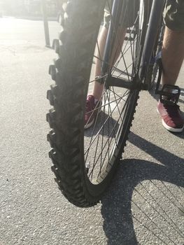 Close up of front bike wheel on asphalt and male legs