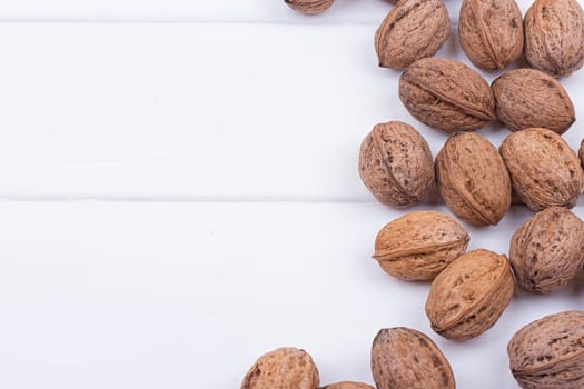 many walnuts on the white wooden background with copy-space