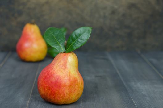 Ripe red pears with green leaves on wooden table