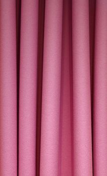 Heavy purple pink pleated felt textile curtain background with portiere drape folds, side view close up