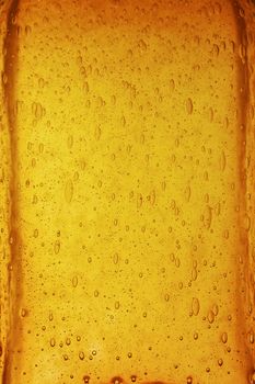 Background texture of solid transparent orange, yellow and brown color glass with pattern of air bubbles, close up