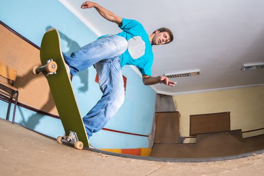 Skateboarder performing a trick on mini ramp at indoor skate park.