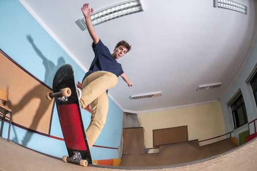 Skateboarder performing a trick on mini ramp at indoor skate park.