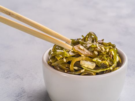 Close up view of kelp seaweed salad with sesame seeds on gray concrete background. Copy space.