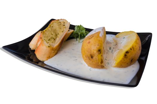 Pell potatoes with herb quark and baguette on a black plate