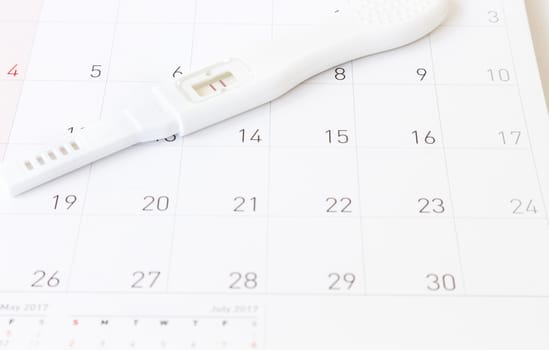 Pregnancy test on calendar background, health care concept
