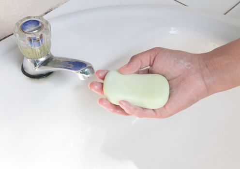 Woman hand holding soap for washing hand with light of sun form park, health care concept