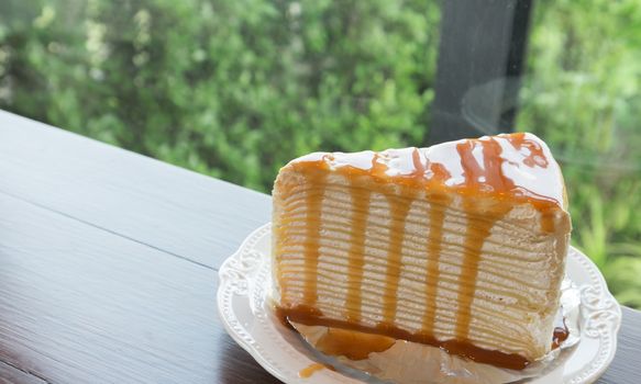 Closeup caramel crape cake on wood table with nature background