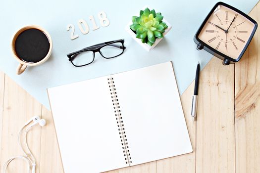 Business, weekend, holiday or new year planning concept : Top view or flat lay of open notebook paper, accessories, wood number 2018 and coffee cup on wooden background, ready for adding or mock up