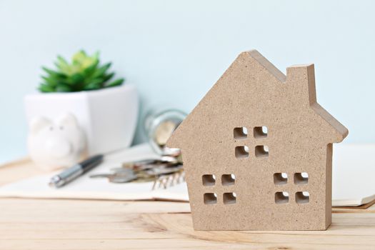 Business, finance, saving money, banking, property loan or mortgage concept : Wood house model in front of coins scattered from glass jar and piggy bank on wooden table