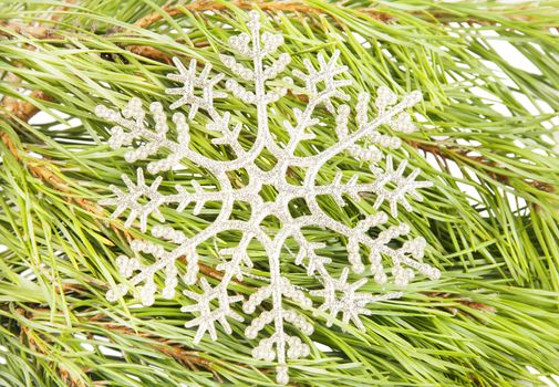 Artificial new year snowflake on fir tree branch background close up