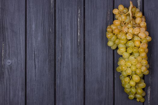 bunch of white grapes on a black wooden background. Rustic style. Place for text. copy-space