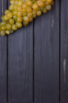 bunch of white grapes on a black wooden background. Rustic style. Place for text. copy-space