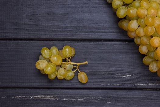 bunch of white grapes on a black wooden background. Rustic style.