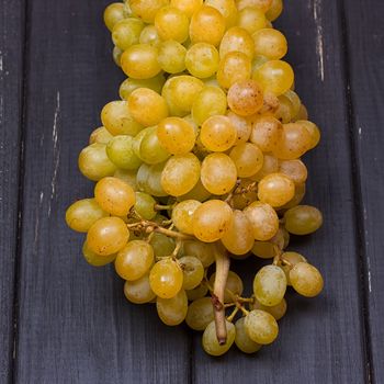 bunch of white grapes on a black wooden background. Rustic style.