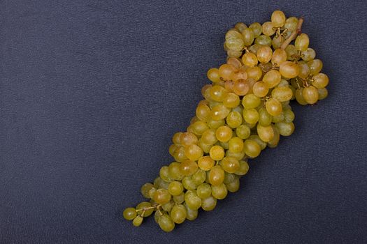 Large grapes cluster amber color on black background. copy-space