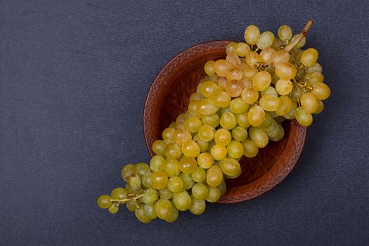 Bowl with a bunch of white grapes on black table. copy-space