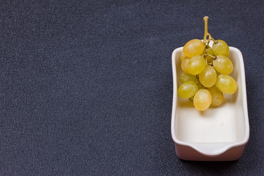 White grapes in a bowl on a black background.copy-space