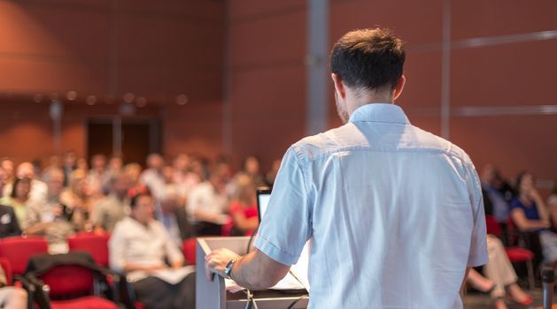 Speaker at Business Conference with Public Presentations. Audience at the conference hall. Entrepreneurship club. Rear view. Horisontal composition. Background blur.