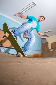 Skateboarder performing a trick on mini ramp at indoor skate park.