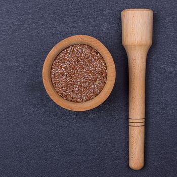 Flax seed in a wooden bowl on a black background