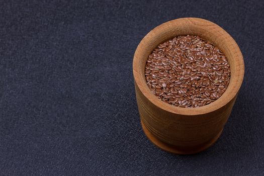 Flax seed in a wooden bowl on a black background