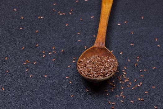 wooden spoon with flax seed placed on a black table